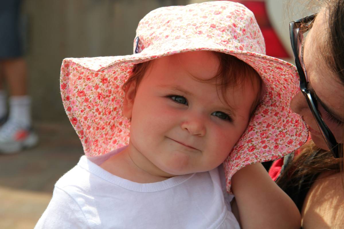Mother holding newborn outdoors with concern; can newborns wear sunscreen